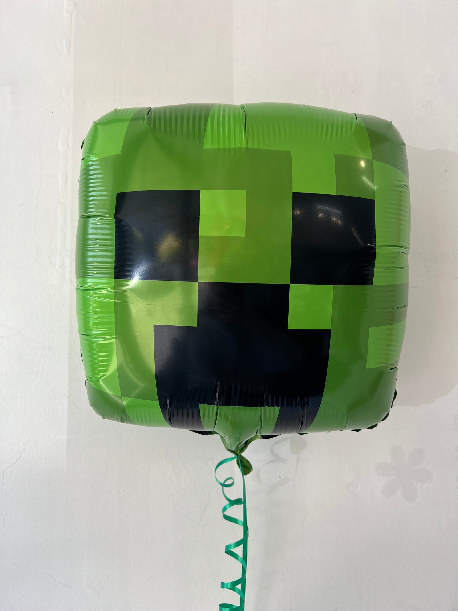 Minecraft Creeper foil balloon by Anagram, featuring a green Creeper character from the popular video game, against a colorful background.