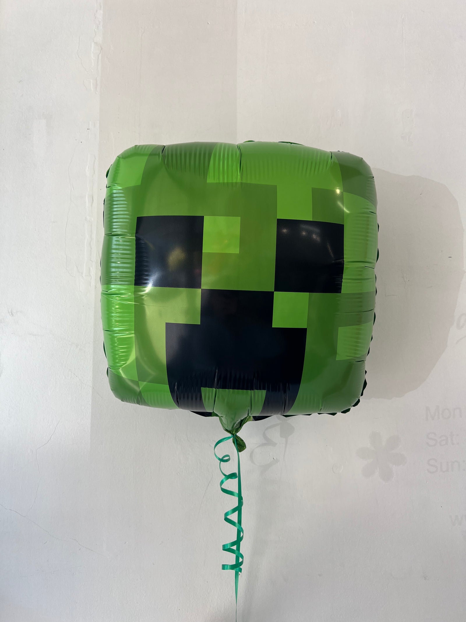 Minecraft Creeper foil balloon by Anagram, featuring a green Creeper character from the popular video game, against a colorful background.